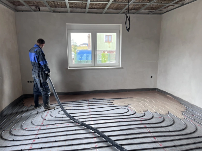 Instalace podlahového topení s hadicemi v nehotovém interiéru.