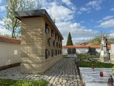 Moderní kolumbárium v hřbitově s kamennou fasádou.