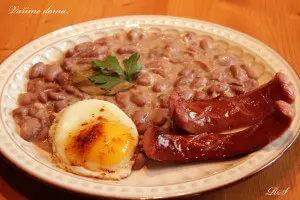 Hot bean stew served with fried sausage, boiled egg and herbs.