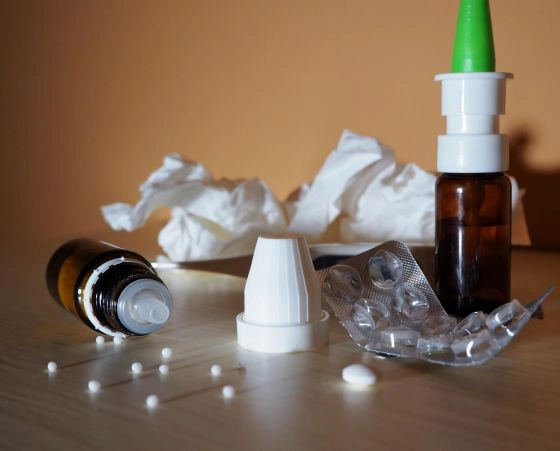 Nádoby s nosními kapkami, tablety a zmačkané kapesníky