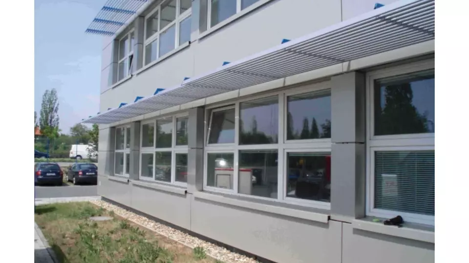 Modern budova s větranou fasádou nad okny pro kancelářský prostor.
