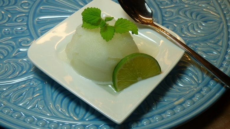 Bílé sorbet s mátou a limetkou na talíři.