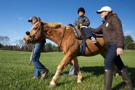 Child riding horse with handlers