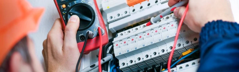 Elektrikář měří napětí v rozvaděči multimetrem.