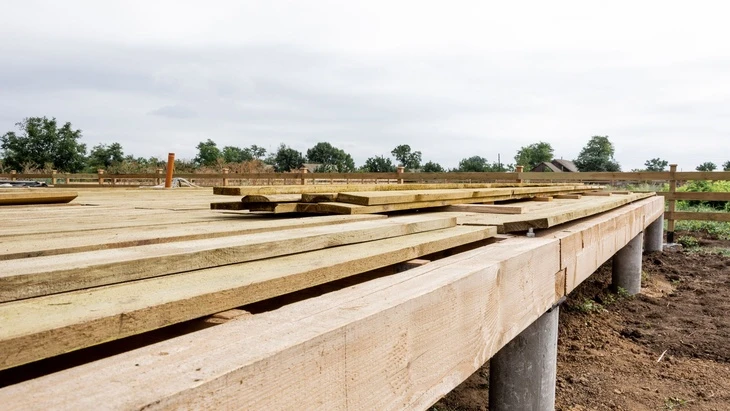 Dřevostavba na patkách s dřevěnými trámy a betonovými sloupy.
