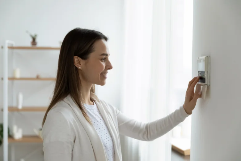 Žena nastavuje chytrý termostat pro úsporu energie.