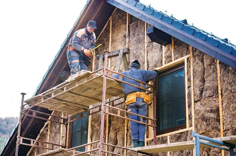 Práce na zateplení dřevěné chaty s izolačním materiálem.