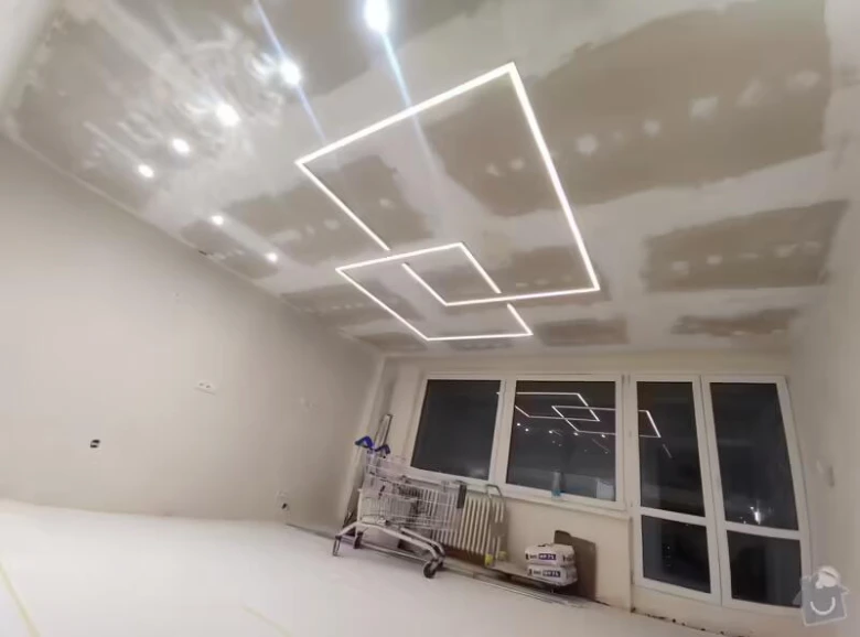 Elektrikář instaluje moderní LED osvětlení do stropu při rekonstrukci interiéru.