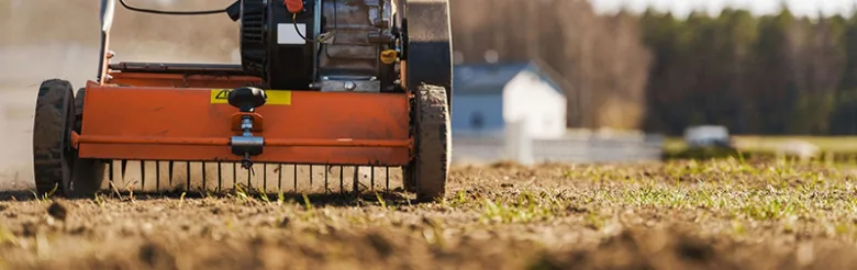Lawn aerator pracuje na trávníku s mladým porostem