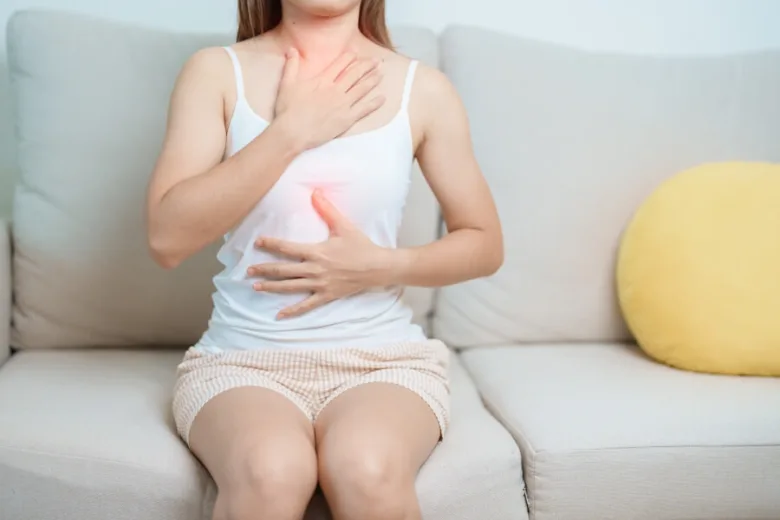 Žena trpící pálením žáhy, drží si hrudník a břicho
