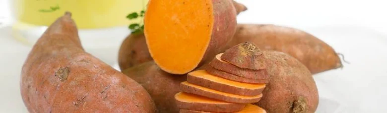 Svíčité batáty s oranžovou dužinou na bílém podkladu.