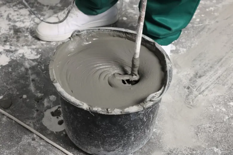 Míchání čerstvého betonu v kbelíku pomocí elektrického míchače.