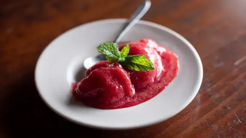Červený sorbet s mátou na bílém talíři