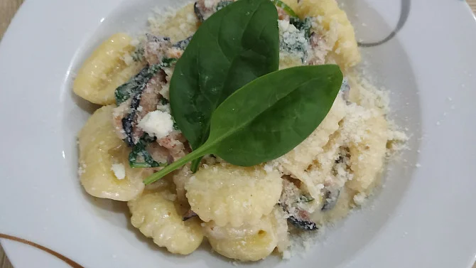 Gnocchi se špenátem a sýrem na bílém talíři