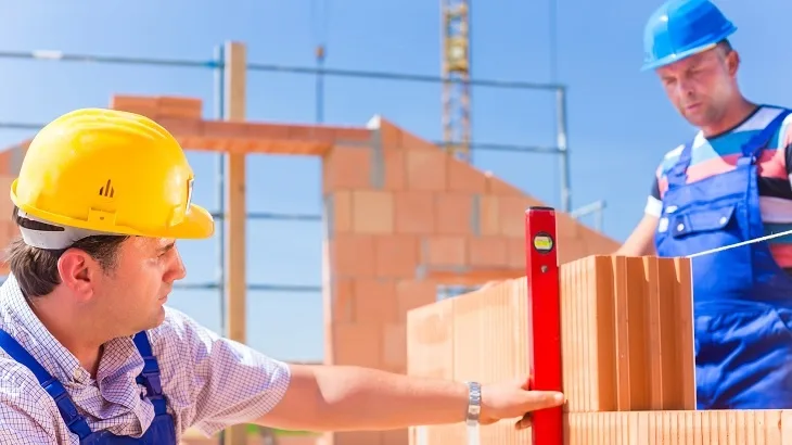 Stavební dělníci kladou cihly na staveništi.