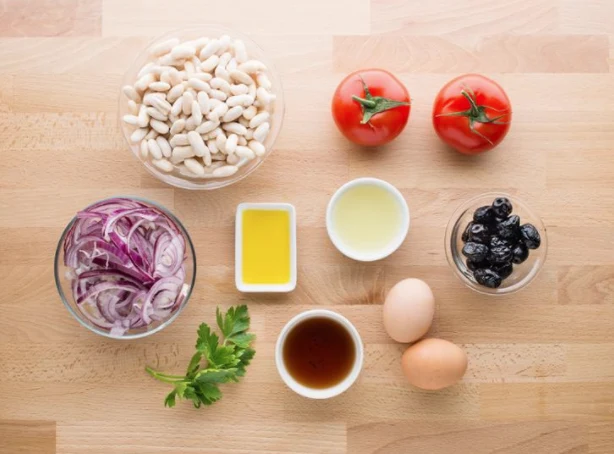 Ingredience pro fazolový salát: bílé fazole, rajčata, červená cibule, olivy, vejce, olej a bylinky
