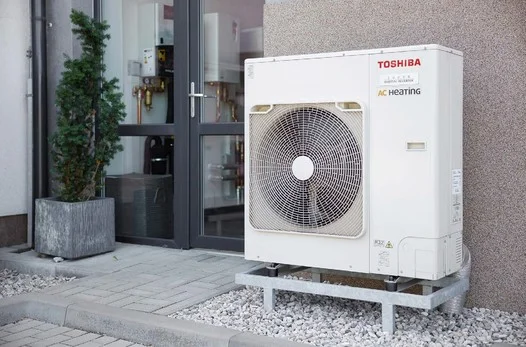 Bílé tepelné čerpadlo Toshiba venku u domu.