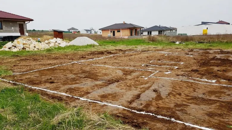 Značení základů domu bílým práškem na zemi před betonováním.