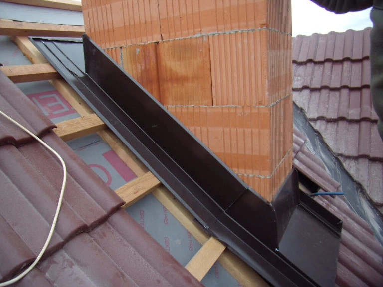 Detailní instalace oplechování komína s kovovým pláštěm.