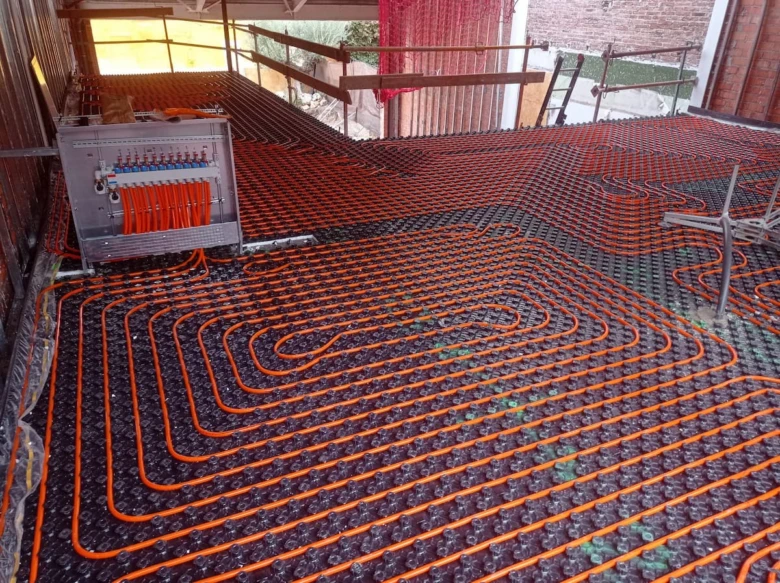 Instalace podlahového topení s oranžovými hadicemi před odvzdušněním.