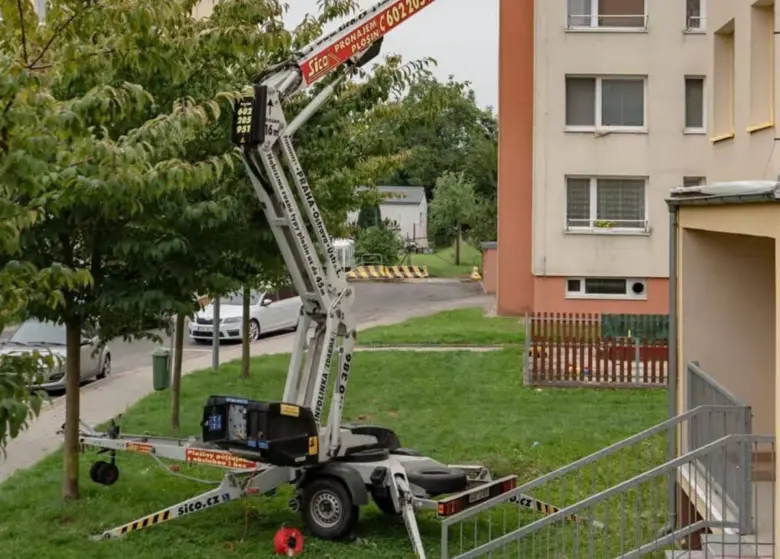 Bilový výškový jeřáb pro rekonstrukci balkonu u bytovky.
