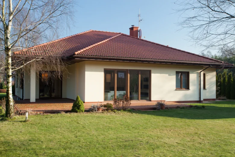Modern dům se světle hnědou fasádou na trávníku.