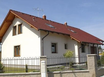 Modern dům se světle hnědou fasádou na pozadí modré oblohy.
