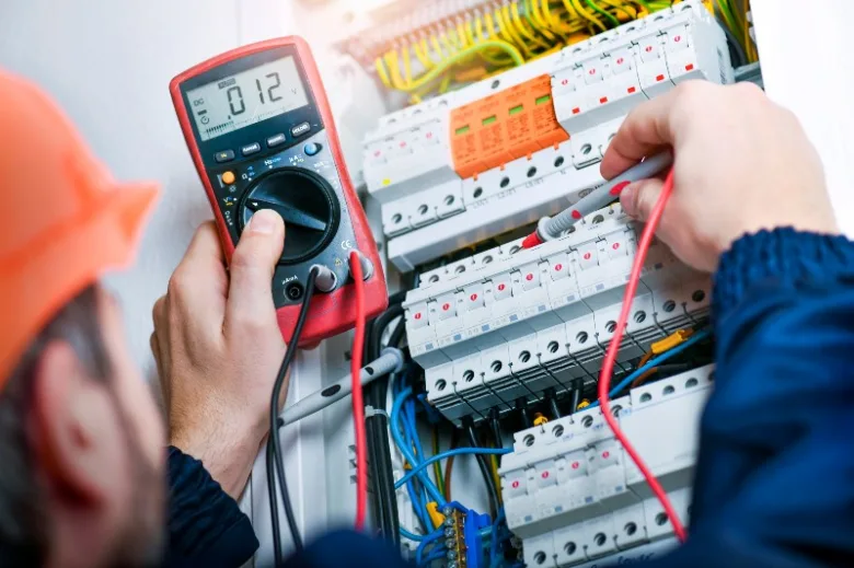 Elektrikář měří napětí v rozvaděči multimetrem.