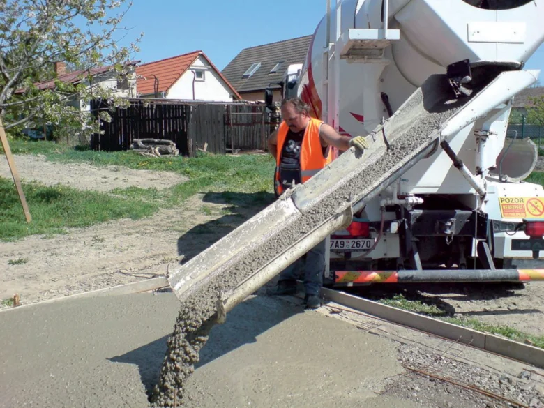Pracovník nalévá beton z míchačky na zem.