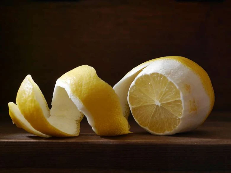 Odloupaný citron s kůrou na dřevěném povrchu.