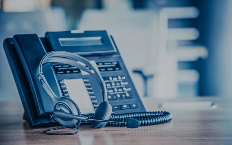 Profesionální telefon s sluchátkem na pracovním stole.