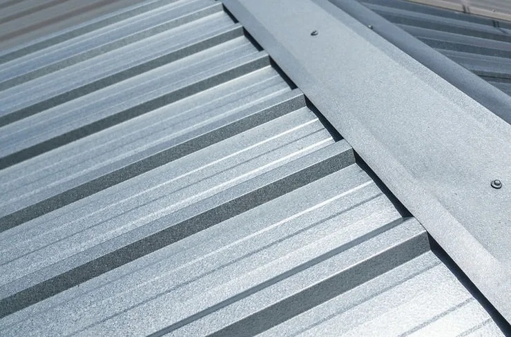 Detail plechové střechy s viditelnými šrouby pro montáž solárních panelů.
