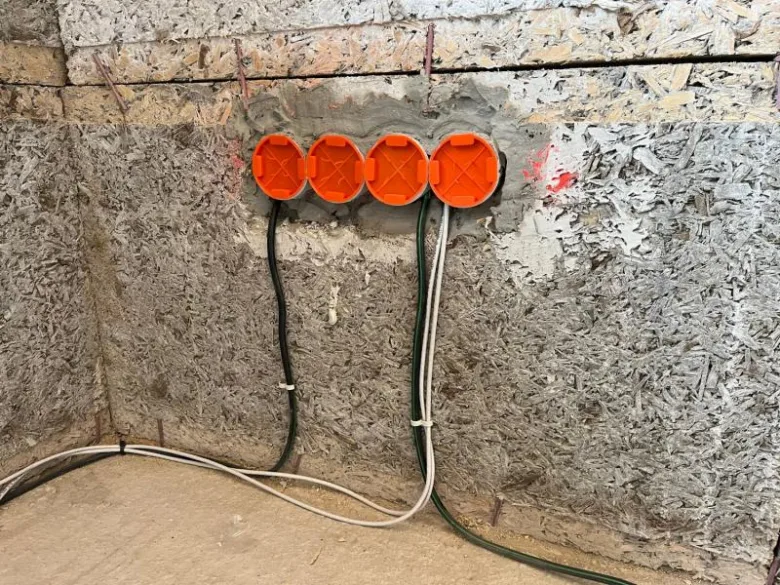 Oranžové elektrické krabice s vedením v nezhotovené stěně.
