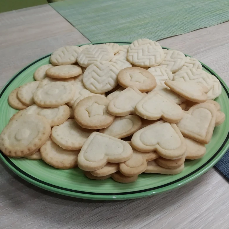Zelený talíř s čerstvě upečenými sušenkami ve tvaru srdce.