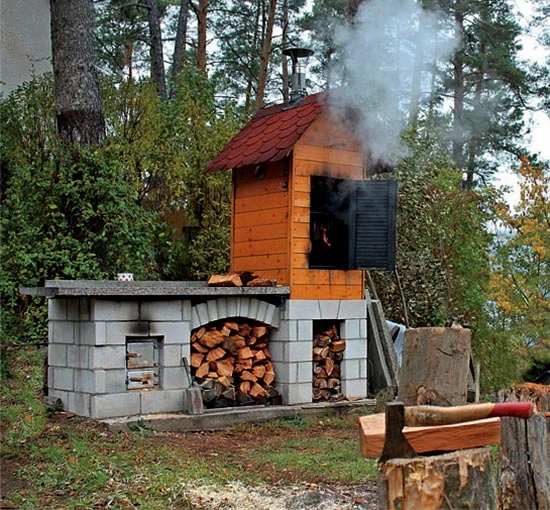 Hotová dřevěná kouřovna s úložištěm drahého paliva venku.