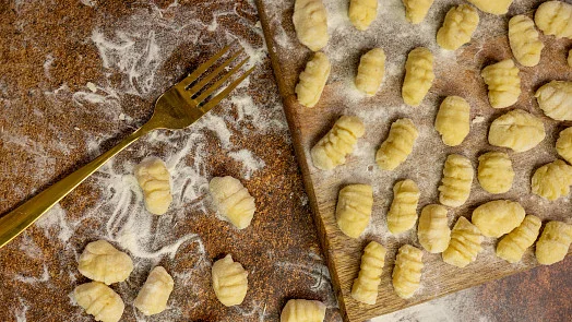 Příprava gnocchi na dřevěné desce s vajíčkem a houbou