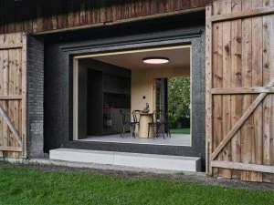 Přestavba stodoly s moderním interiérem viditelným zvenku.