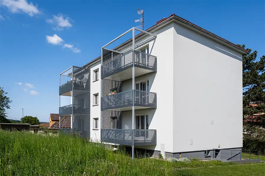 Moderní balkony s kovovými mřížemi na bílém domě.