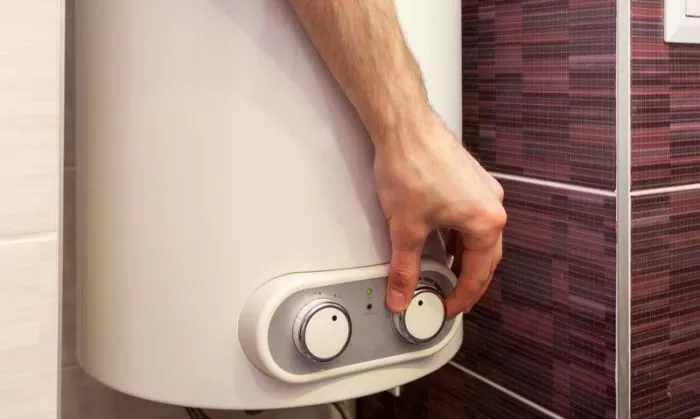 Ruka nastavuje regulaci elektrického kotle pro úsporu energie.