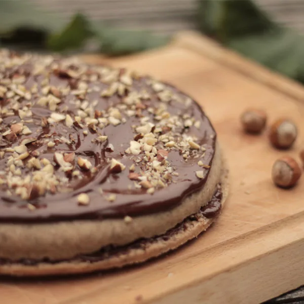 Buchta s Nutelou na dřevěném podnosu s ořechy.