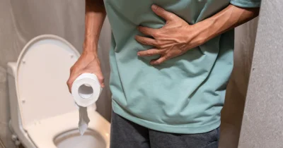 Muž s bolestí břicha flushuje záchod kvůli trávicím problémům.
