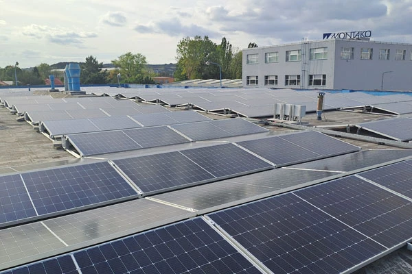 Fotografie fotovoltaických panelů na střeše průmyslové budovy.