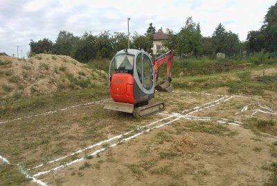 Bager na stavbě u zakreslených základových pasů.